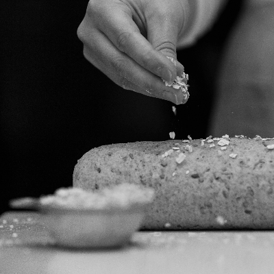 A loaf of sprouted bread being sprinkled with oats before baking