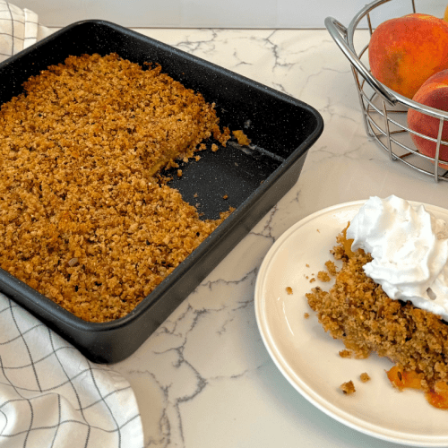 Photo of Alexis’s Peach Sprouted Breadcrumb Betty Dessert plated and topped with coconut whip