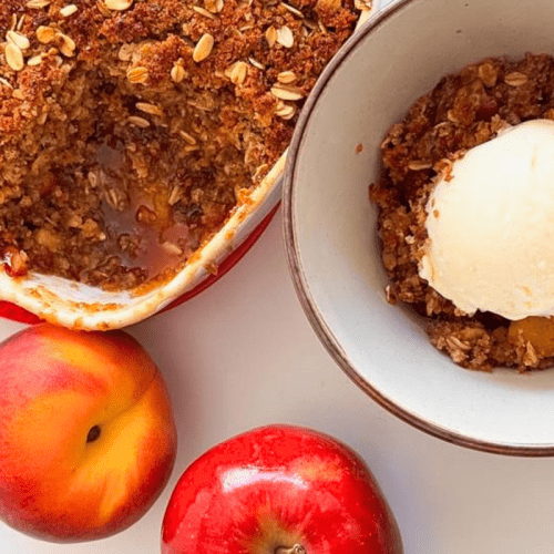 A bowl of Ray’s Peach & Apple Betty Dessert with Sprouted Breadcrumbs topped with plant-based vanilla ice cream