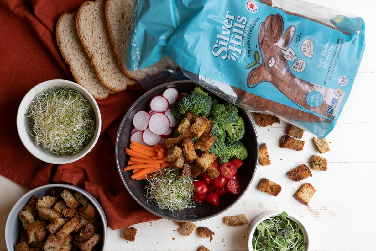 Garlicky sprouted croutons in a salad bowl with a bag of Silver Hills Bakery Soft Wheat bread