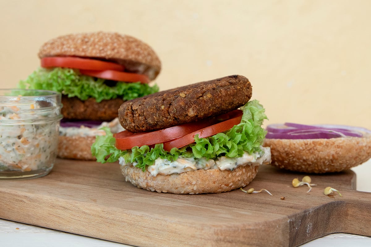 Sprouted Green Lentil Burgers with Vegan Pickle Dip Ranch Sauce on a Silver Hills Bakery sprouted whole grain Sesame Burger Bun, topped with fresh lettuce, tomatoes and onions