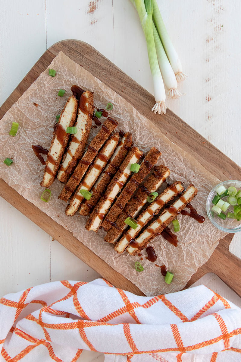 Crispy Air Fryer Tofu Katsu Sando with Sprouted Breadcrumb crust, sliced and drizzled with Homemade Vegan Katsu Sauce